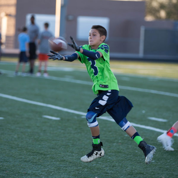 Young receiver reaching out to catch a pass during a drill