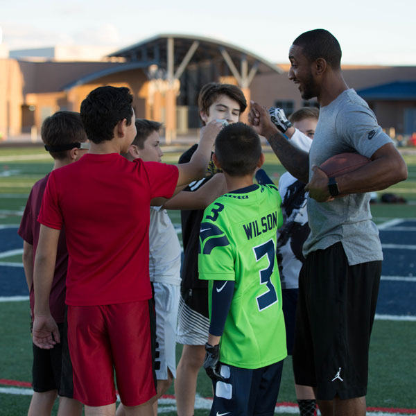 Coach high-fiving a group of camp players on the field
