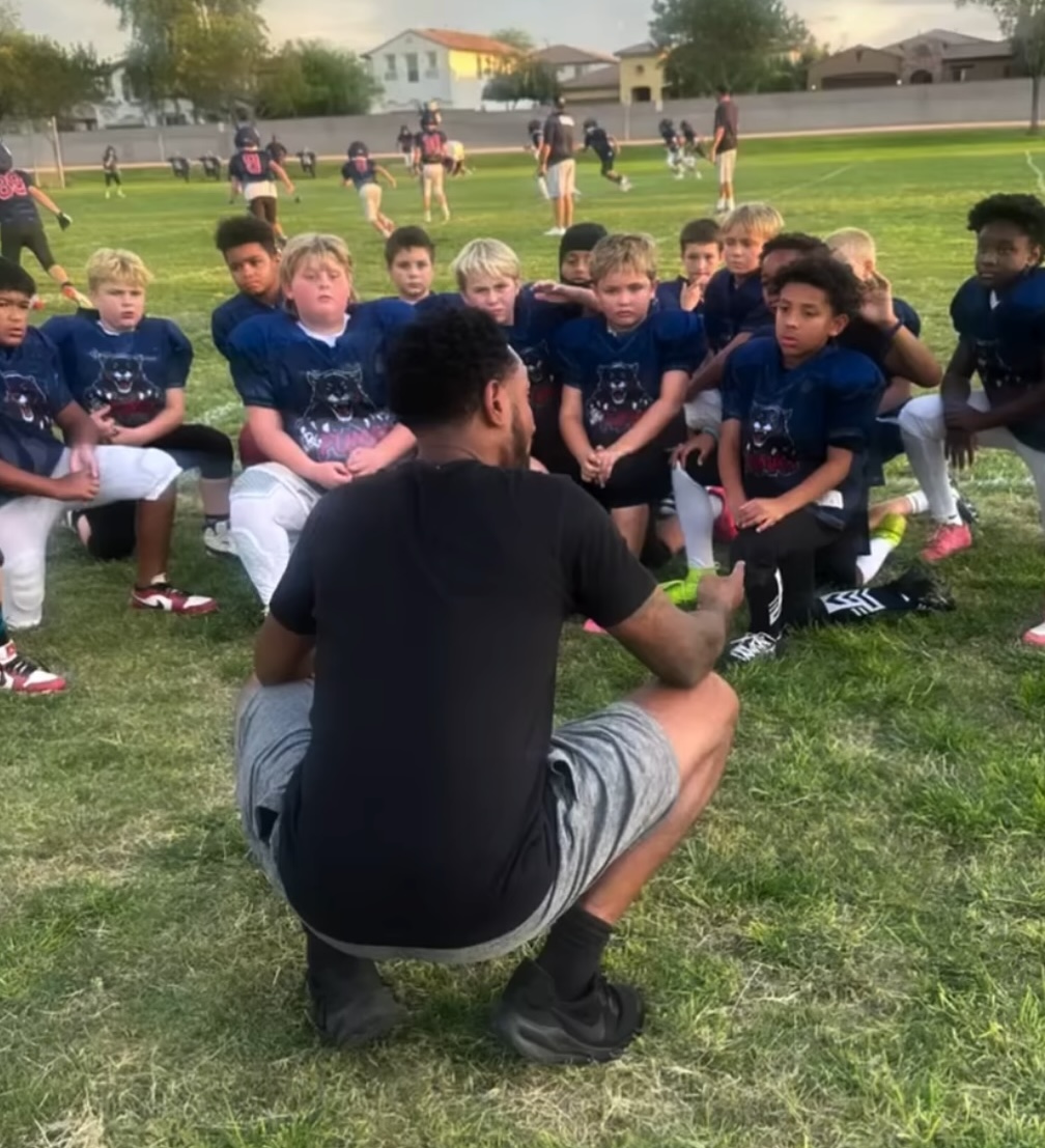 Coach kneeling to talk with a youth team gathered in their jerseys