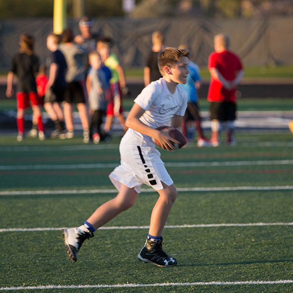 Young player running with the ball during a camp drill